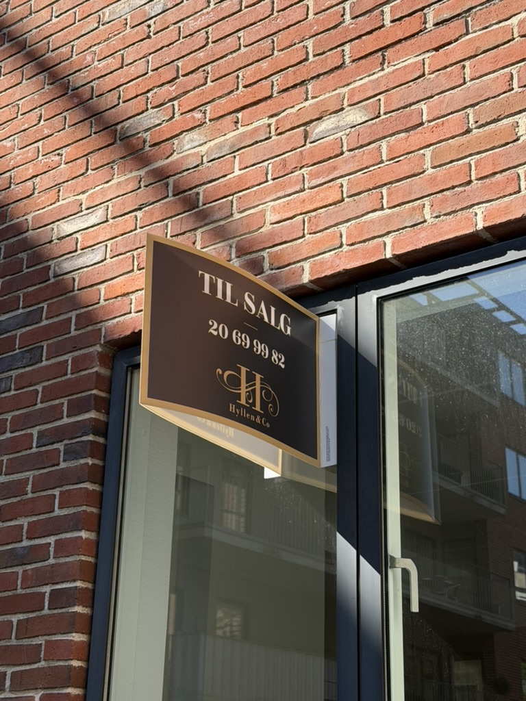 Brunt vinkelskilt med guldkant monteret på vindueskarm