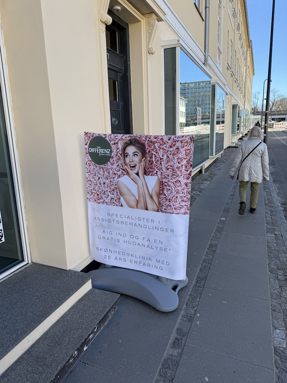 Skiltepose monteret på gadeskilt foran butik